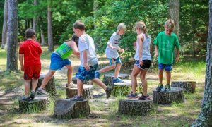 sumemr camp kids walking on tree stumps