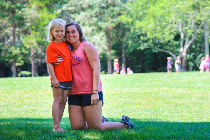 female staff member with young girl posing for camera on lawn